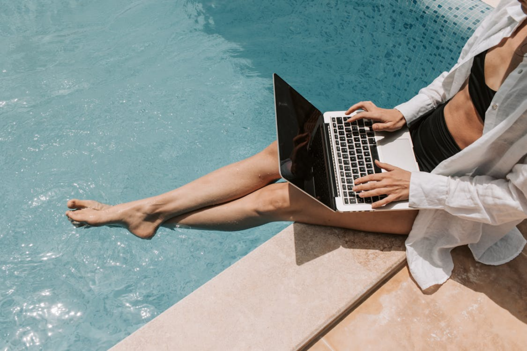 Remote worker using laptop by a pool, showing work-life balance by country