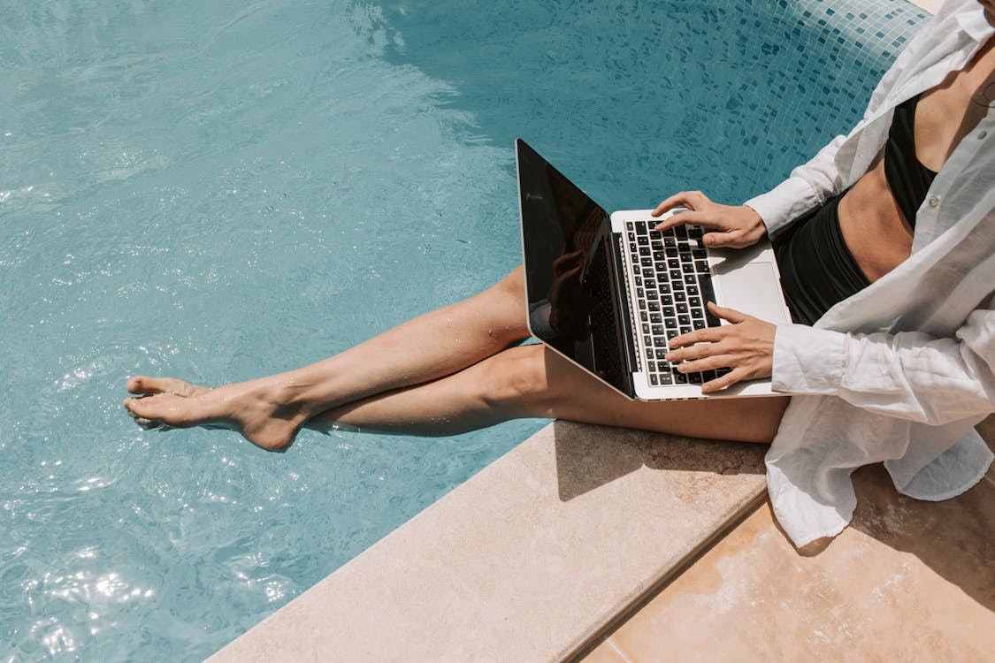 Remote worker using laptop by a pool, showing work-life balance by country